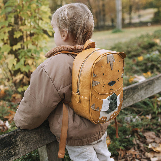 Kind trägt den Rucksack Tiger auf einem Ausflug ins Grüne. 