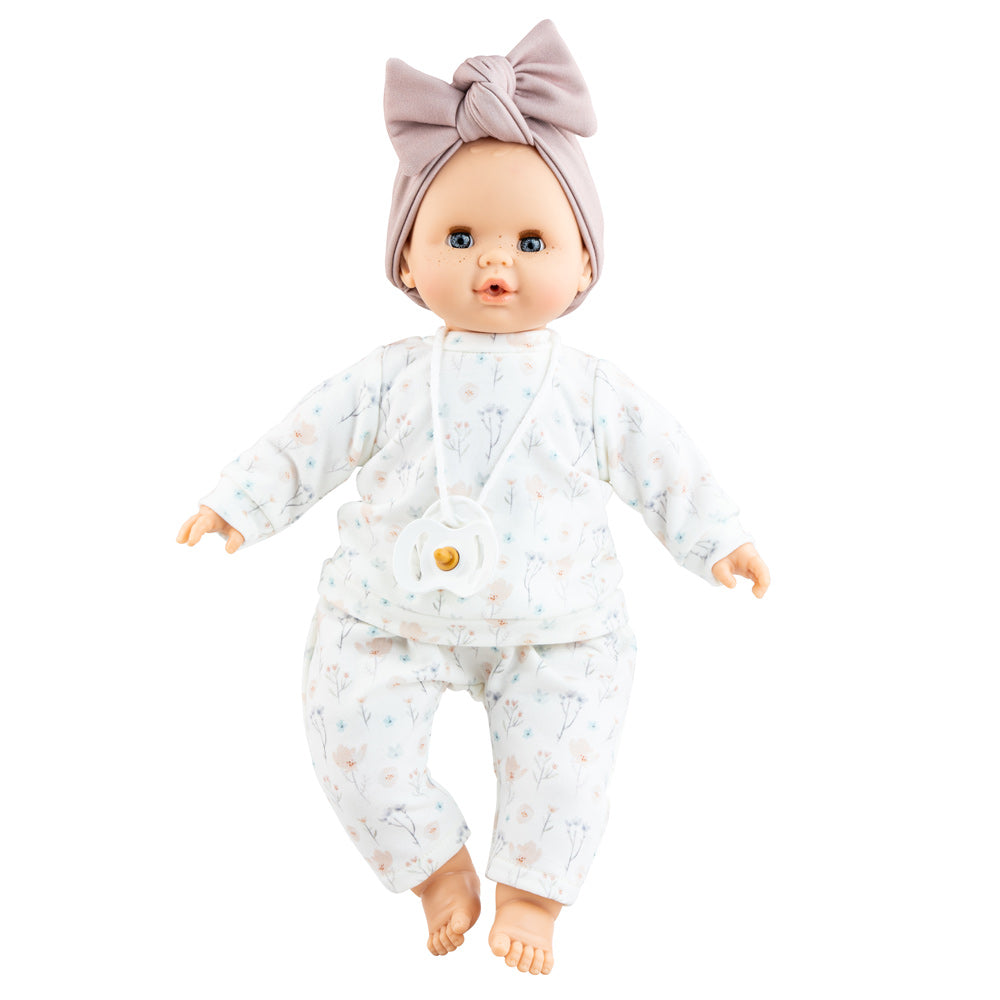 Puppe Liv hat blaue Augen und leichte Sommersprossen und trägt ein schlichtes Puppenoutfit mit Pulli und Hose sowie ein fliederfarbenes Stirnband. 