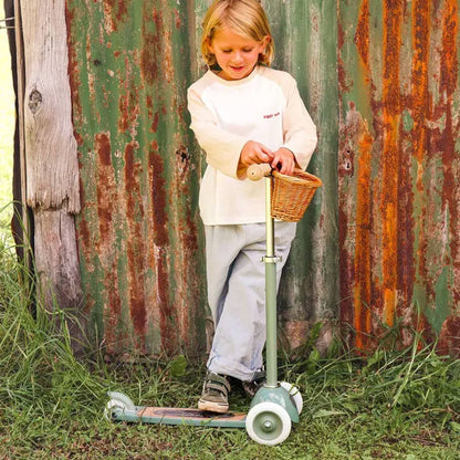 Junge steht auf dem Kinderroller von Banwood in der Farbe olivgrün