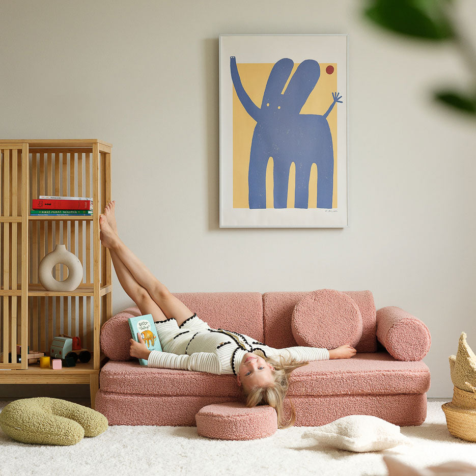 Mädchen liegt auf dem Spielsofa von Wigiwama in der Farbe Guava. Es ist ein schöner rosa-Ton, der sehr harmonisch aussieht. 