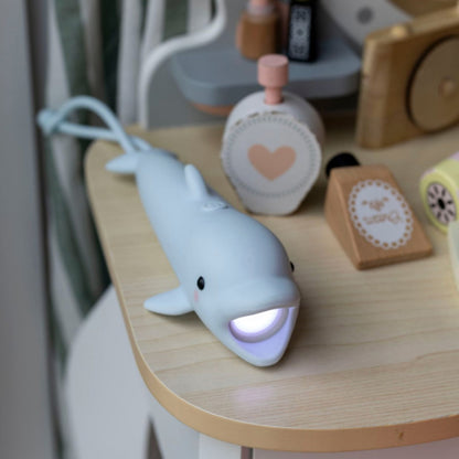 Die Taschenlampe Delfin für Kinder liegt im Kinderzimmer und leuchtet