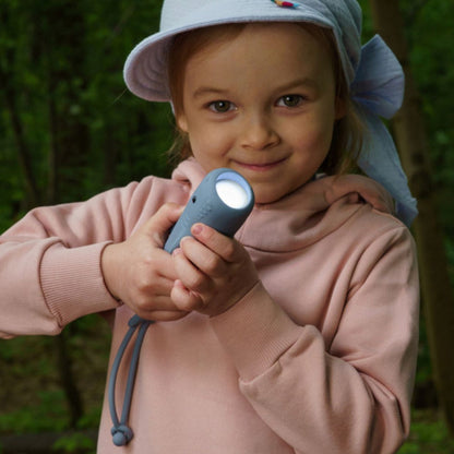 Mädchen leuchtet mit der Kinder-Taschenlampe Hai draußen im Wald